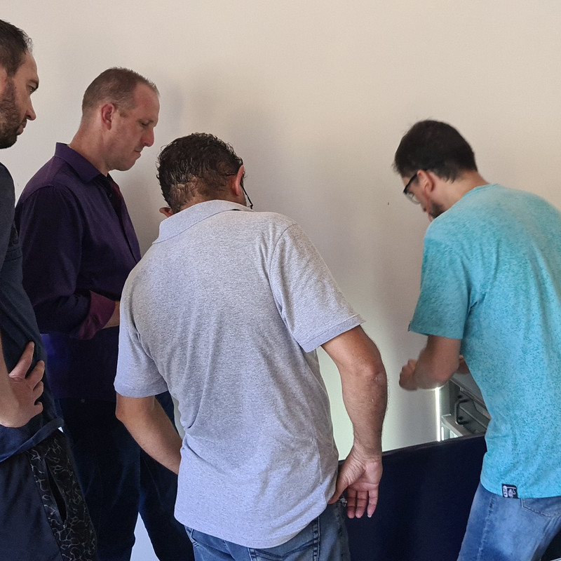 Treinamento prático de soldagem laser com participantes em ambiente industrial